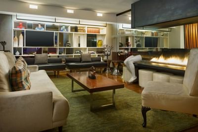 Chic lounge with a fireplace by leather sofas under soft lights at The J House Greenwich