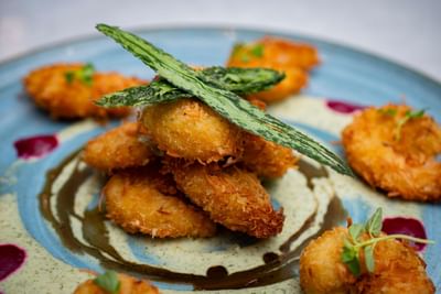 Colorful plate of crispy fried shrimp topped with fried greens served in Restaurante Las Palmas at Dann Carlton Cali