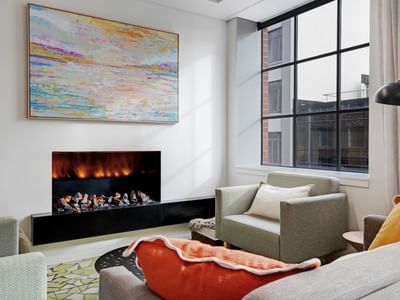 Modern living room with electric fireplace, colorful abstract art, and city view at UniLodge Auckland Central.