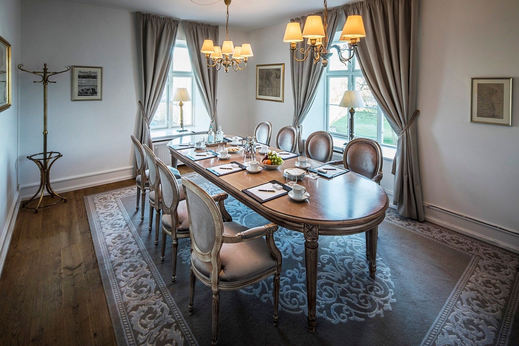 Classic meeting room featuring oval table and elegant drapes with vintage brass coat rack at Warwick Denmark