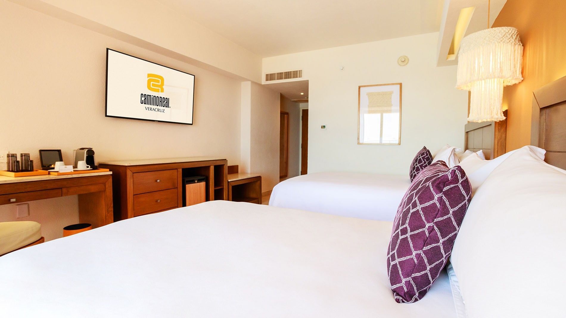 Perspective shot of 2 Double Camino Real Club featuring purple patterned pillows and a large wall TV at Camino Real Veracruz