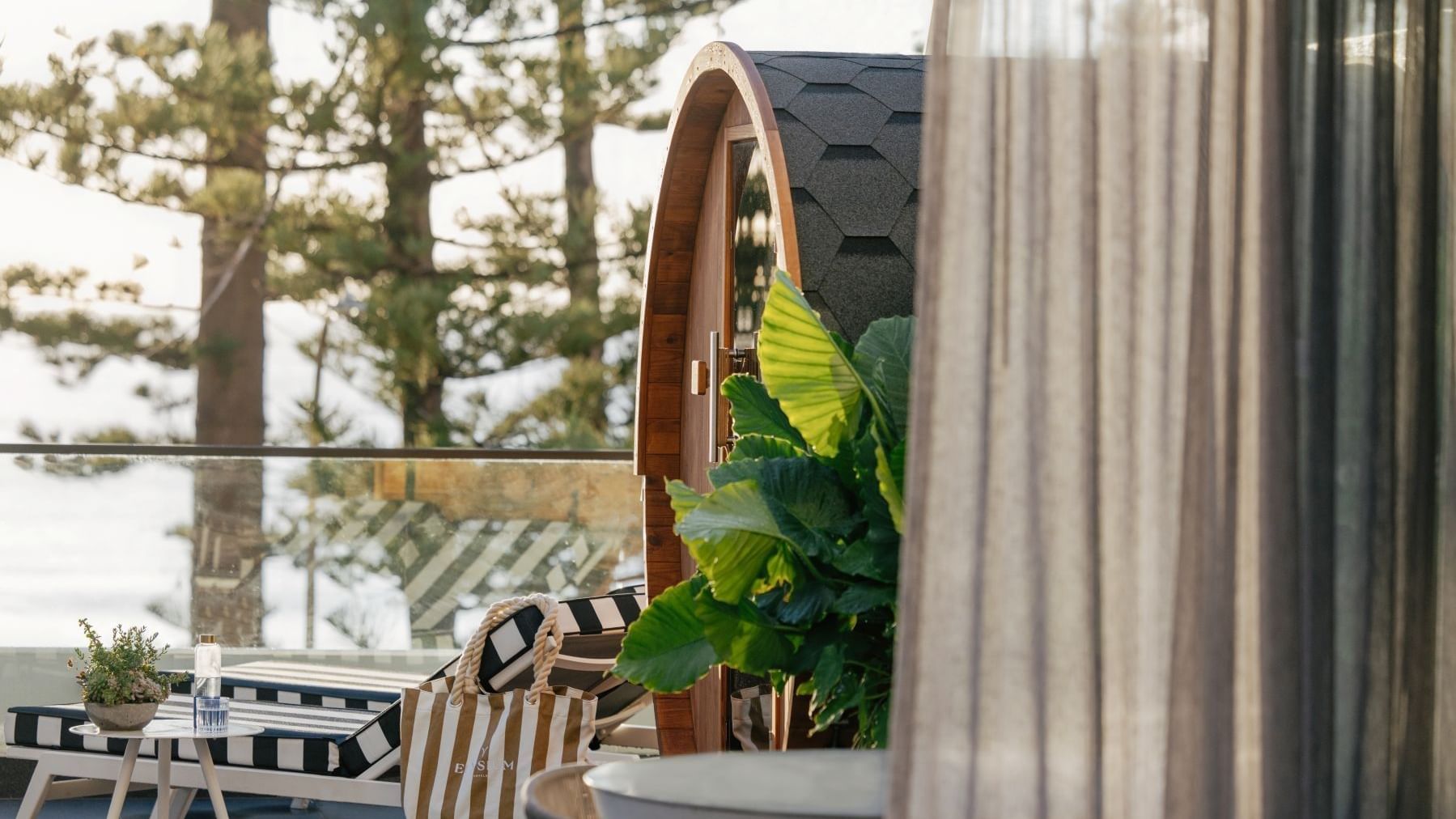 Wellness Two Bedroom Suite at Elysium Manly by tropical leaves under a shingled roof near a striped lounger & canvas tote bag