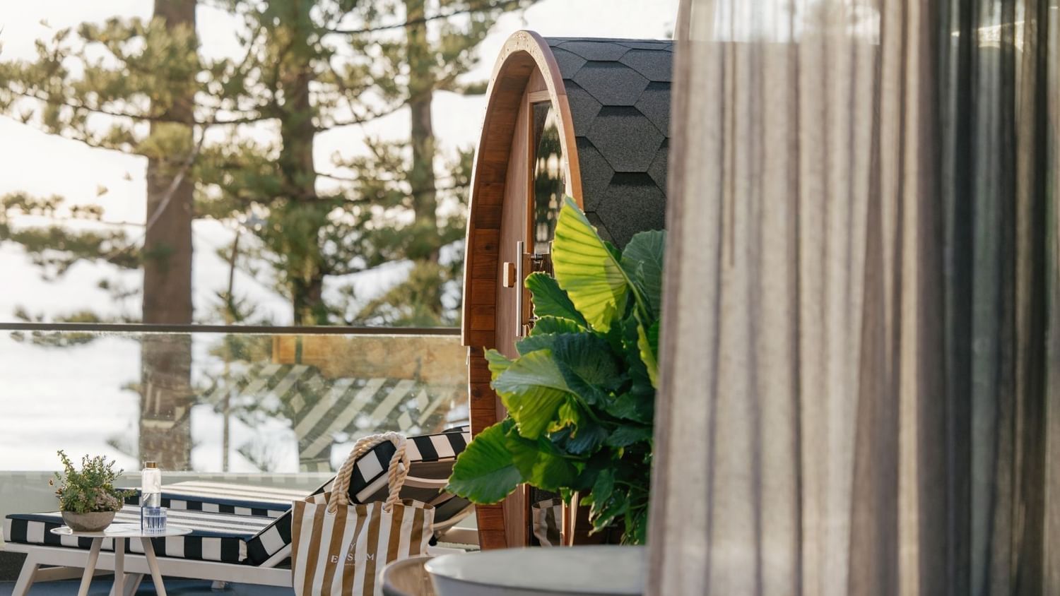 Wellness Two Bedroom Suite at Elysium Manly by tropical leaves under a shingled roof near a striped lounger & canvas tote bag