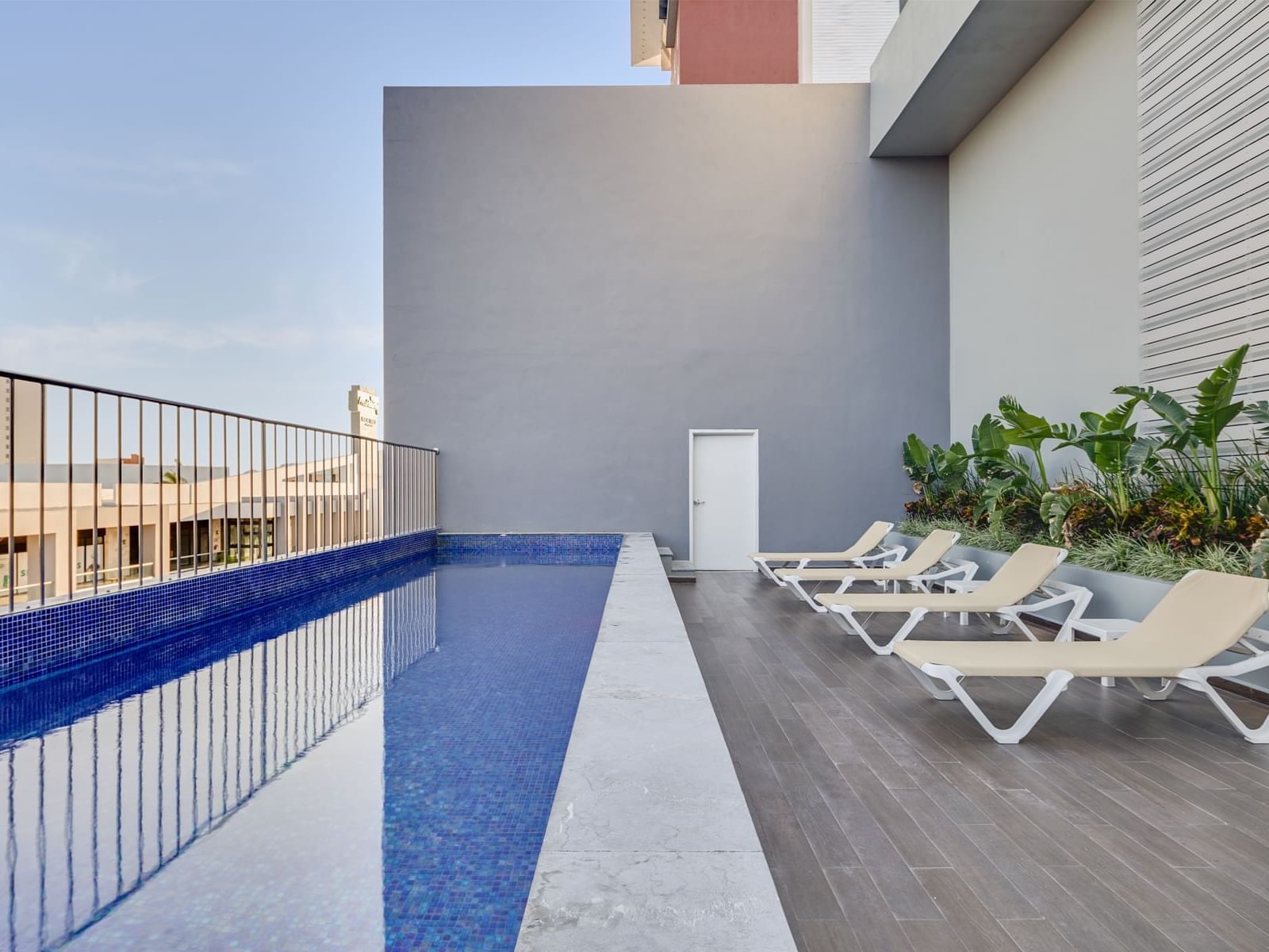 Outdoor pool with comfortable lounge chairs overlooking buildings at one Mazatlán