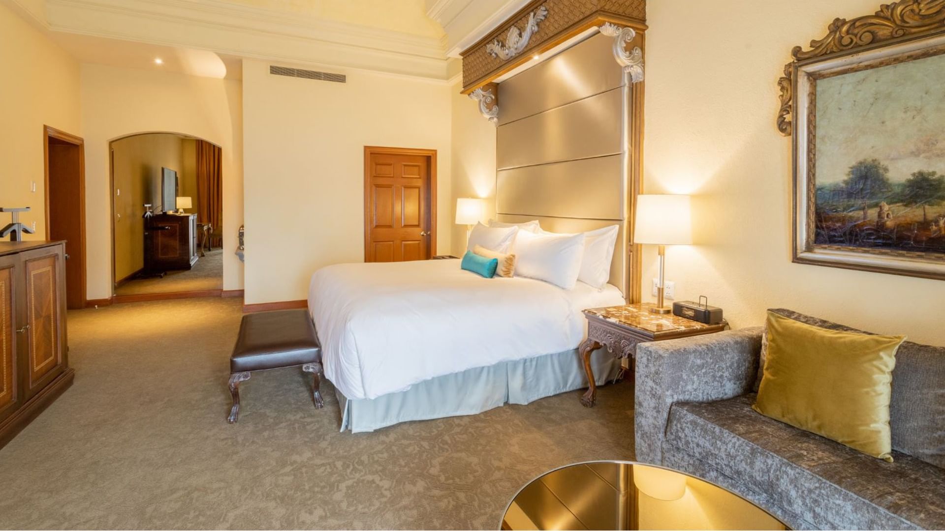 King Presidential Suite showing a tall silver headboard and a cozy velvet sofa area at Quinta Real Monterrey