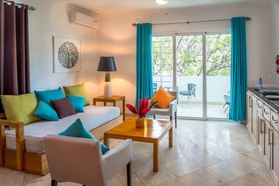 Colorful sofa & armchairs around a table by sliding doors to a balcony in Junior Executive Suite at Hotel Montana Haiti