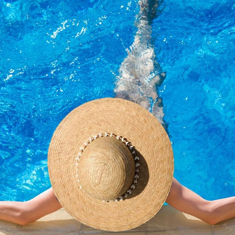 Woman in a hat relaxing in pool at Warwick Doha