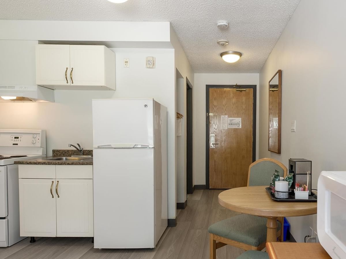 Coast Queen with Kitchenette featuring white appliances, round dining table, and wood-style flooring.