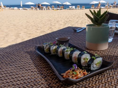 Platter of sushi rolls and a small succulent on a table by the beach in Tortugas restaurant at Hacienda Del Mar Los Cabos