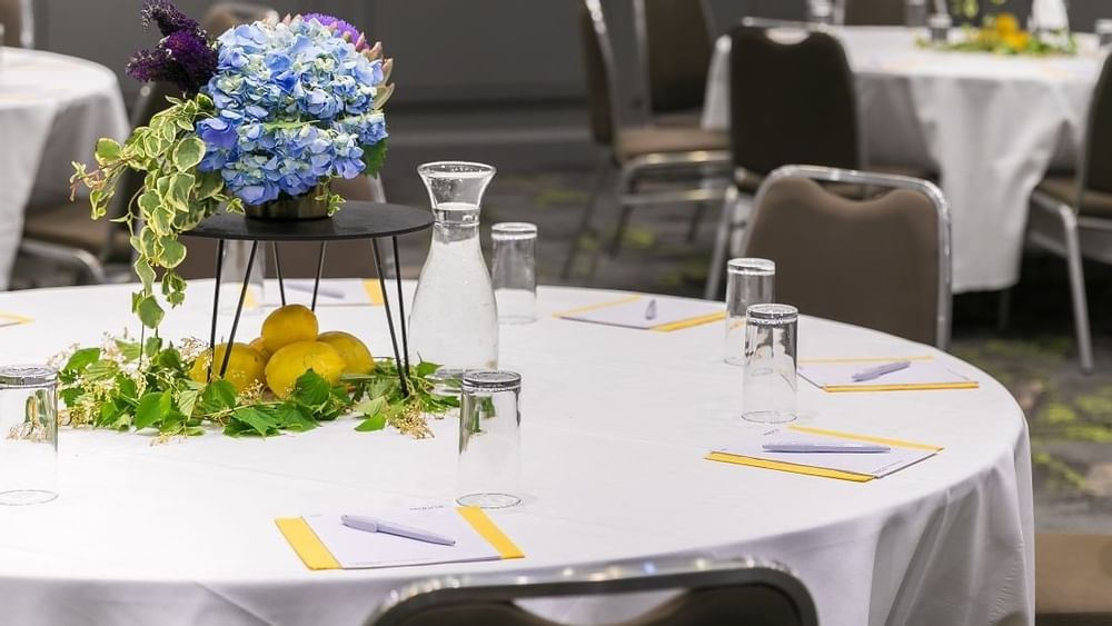 Close-up of setup table adorned with blue floral centerpiece in Grand Ballroom at Novotel Sydney International Airport