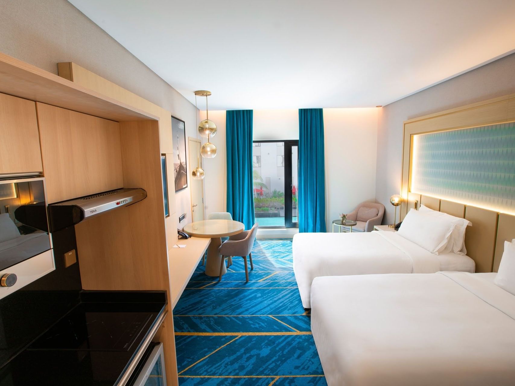 Hotel room with two beds, a desk, a chair, and a blue carpet with gold stripes.