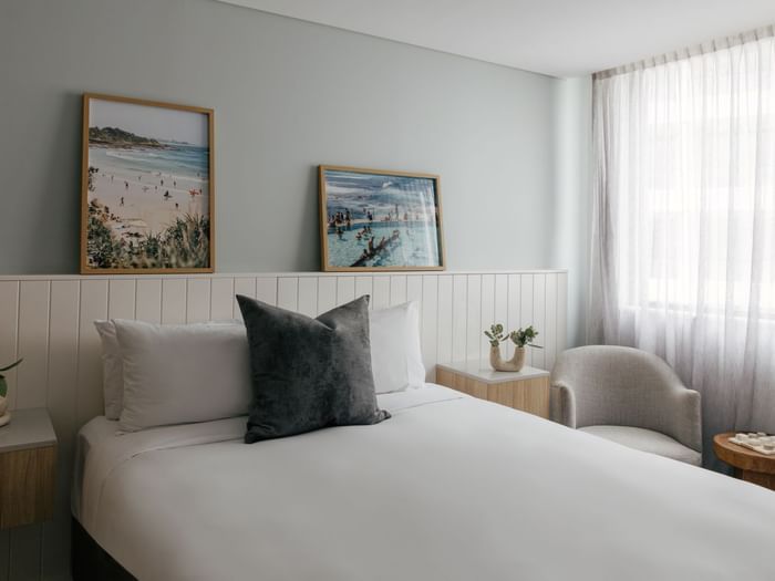 Village Queen at Elysium Manly, featuring a grey cushion on a bed by an armchair, one of the best places to stay in Manly