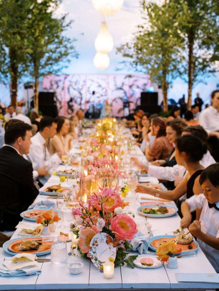 Group of people dining together in a wedding reception in the evening seated around a lengthy table at The Clifton