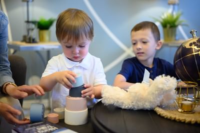 Two young kids playing with colorful plastic stacking blocks and a fluffy teddy bear at Rodd Moncton