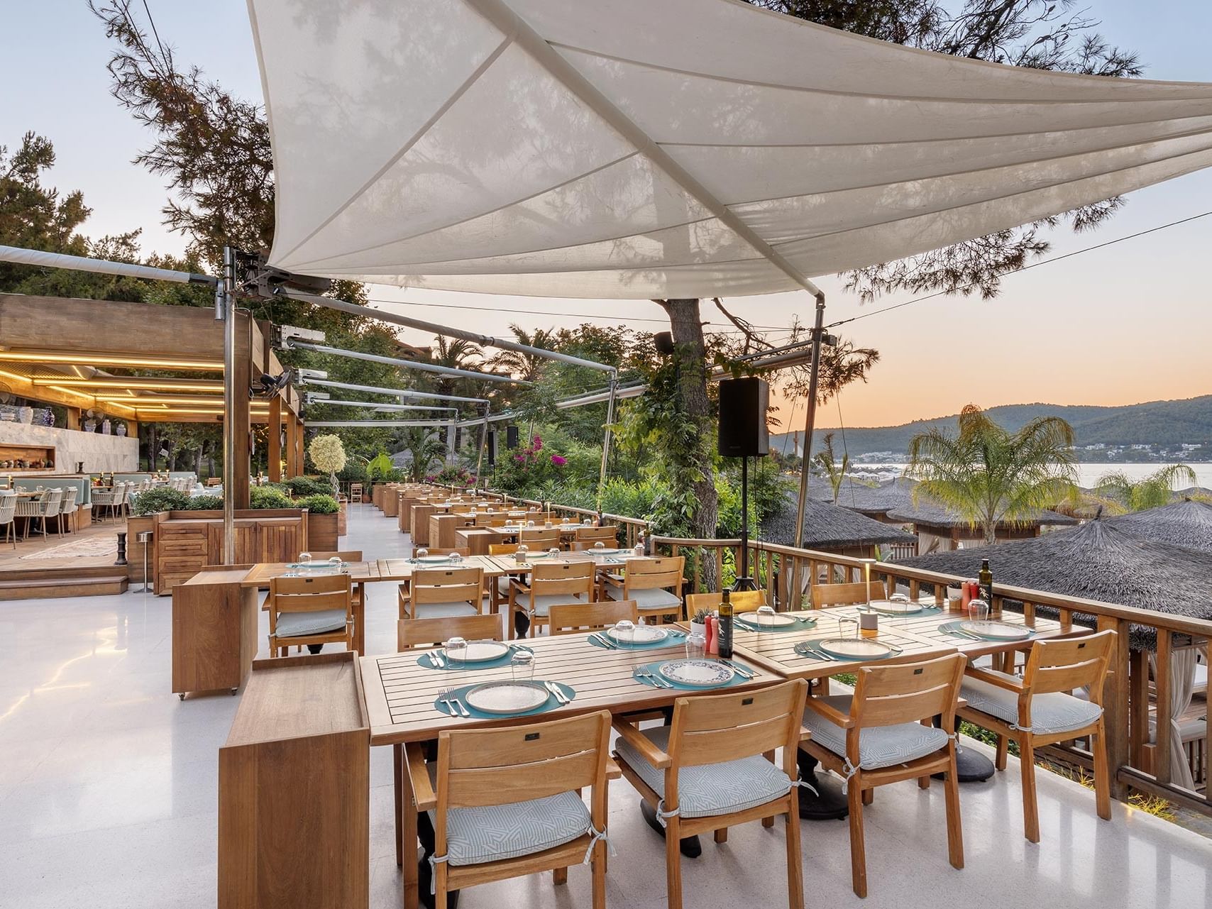 An open-air restaurant at Titanic Luxury Collection Bodrum, set against a peaceful sea view in the evening sun.