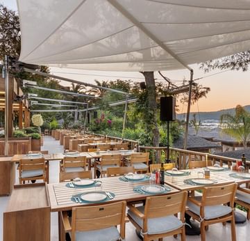 Открытая обеденная зона ресторана Hasir с видом на море — наслаждение вкусом и природой в Titanic Luxury Collection Bodrum.