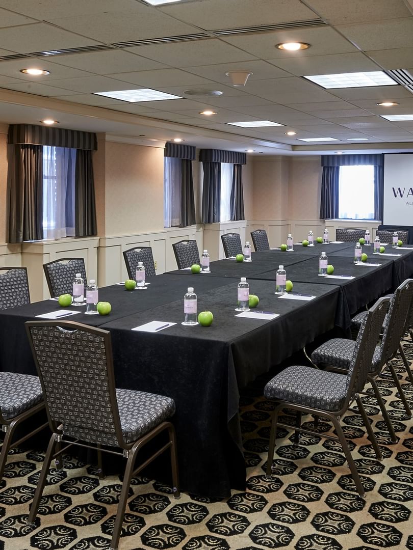 Long table setup facing projector screen near window in the Olmsted Room at Warwick Allerton Chicago