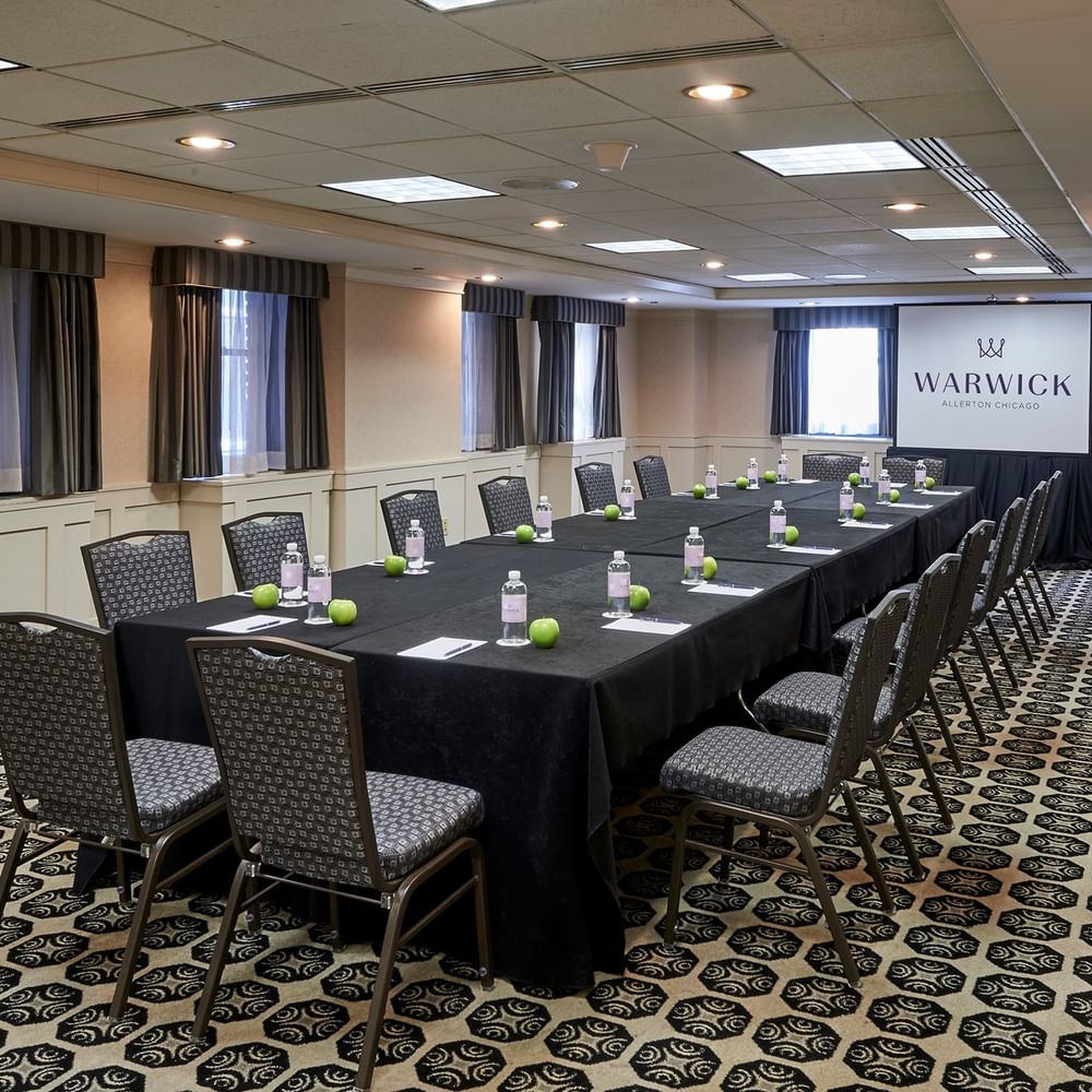 Long table setup facing projector screen near window in the Olmsted Room at Warwick Allerton Chicago