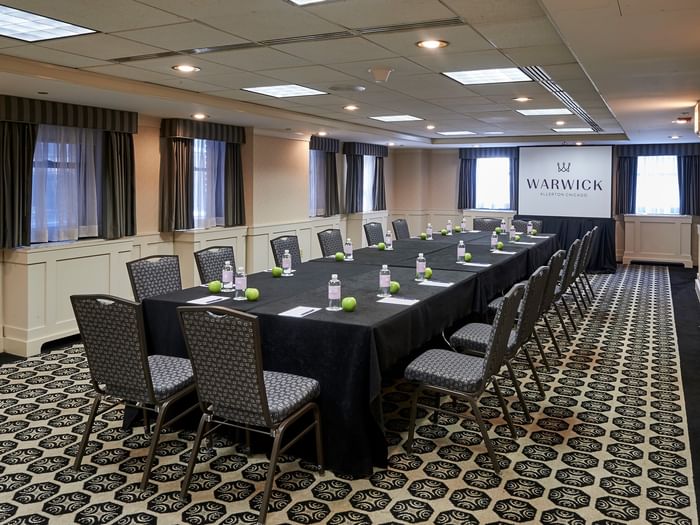 Long table setup facing projector screen near window in the Olmsted Room at Warwick Allerton Chicago