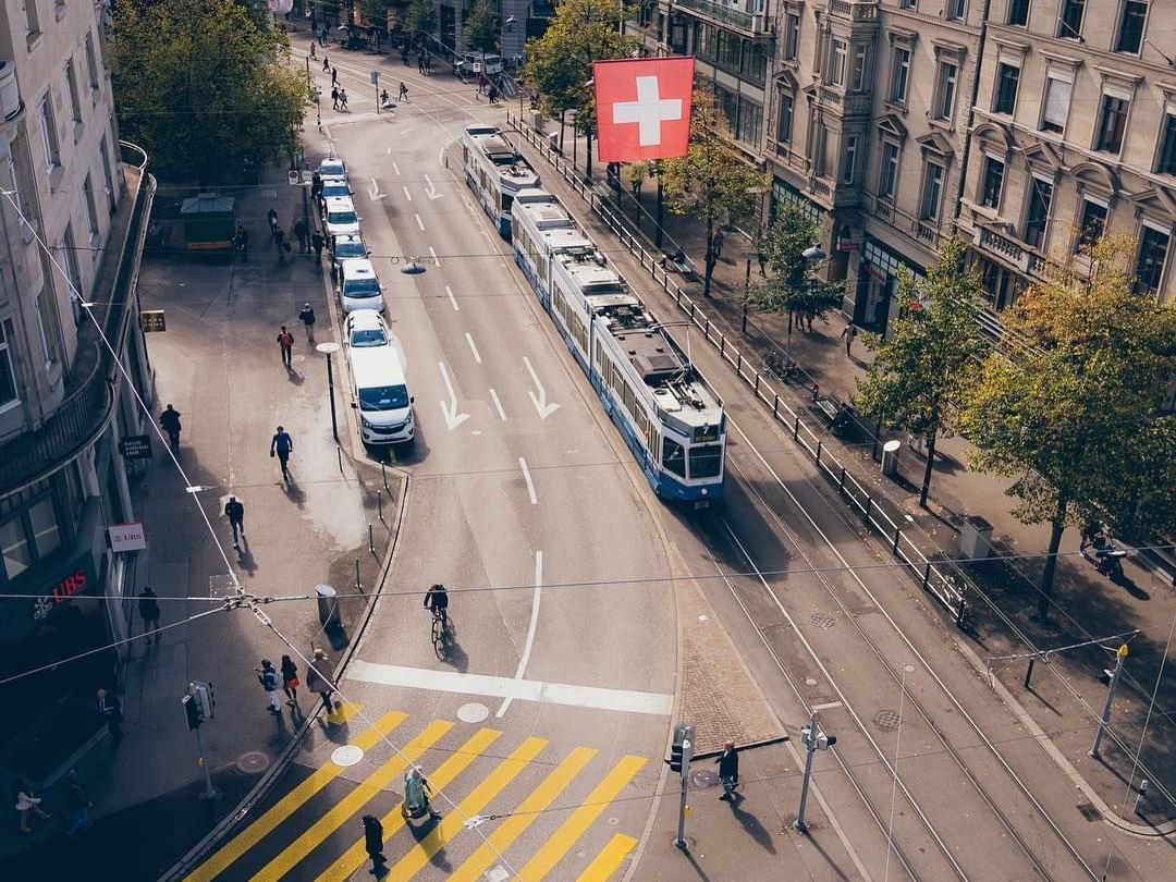 A bustling street featuring a tram alongside parked and moving cars near Best Western Spirgarten