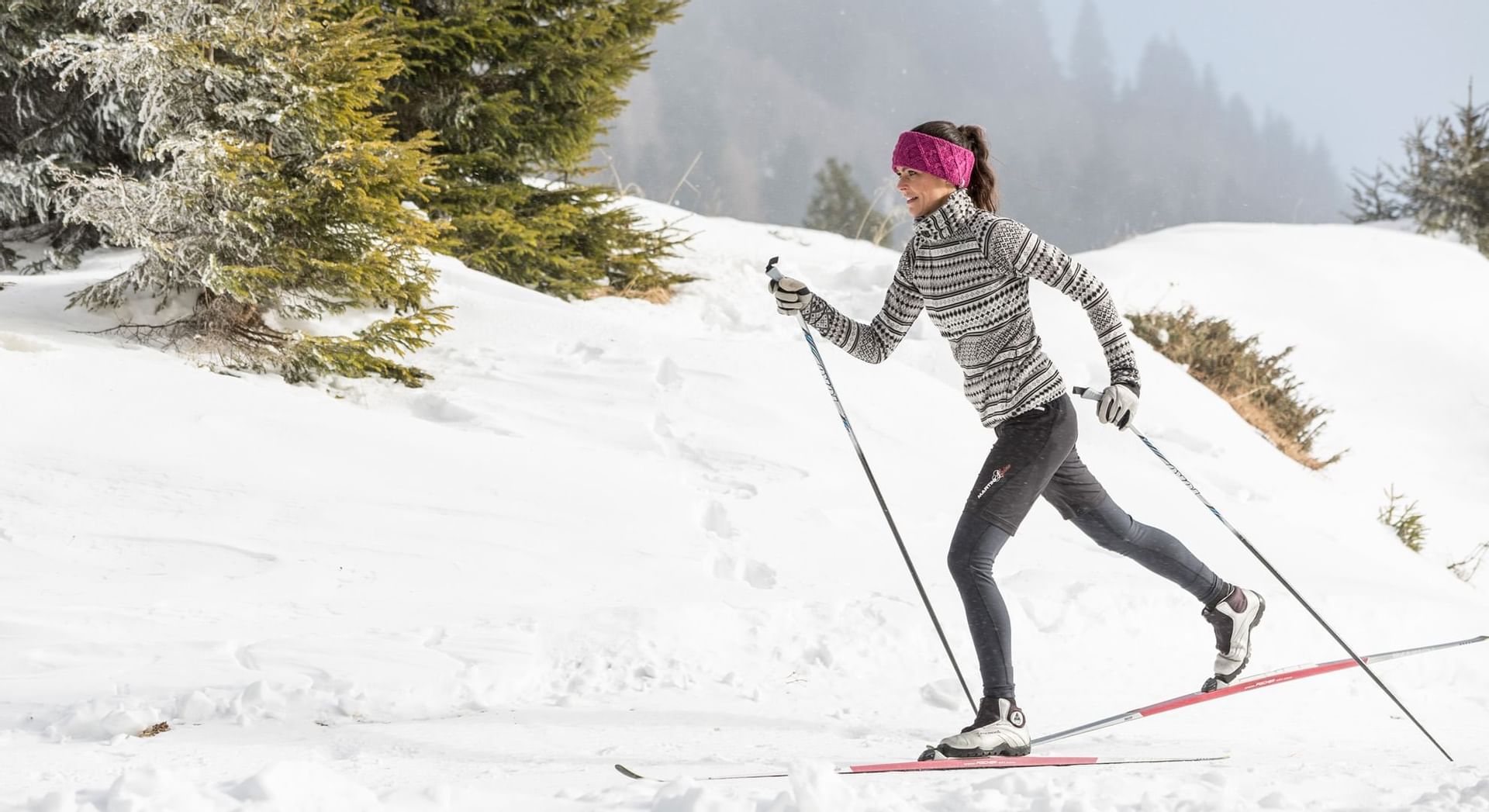 A woman skiing by the snowy mountains near Falkensteiner Hotels