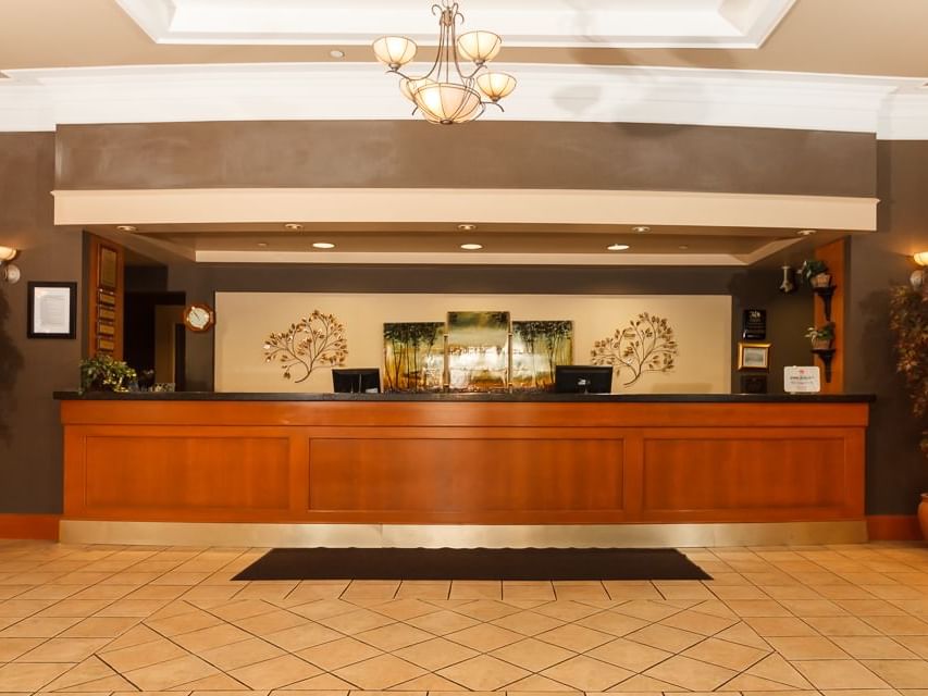 Reception desk with laptops and chandeliers nearby at The Glenmore Inn & Convention Centre