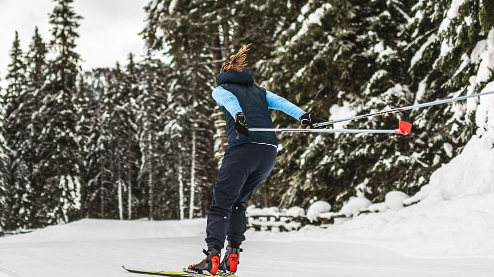 Person cross-country skiing in a snowy forest near Falkensteiner Hotel Antholz