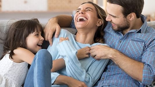 family sitting on couch and Mom laughing