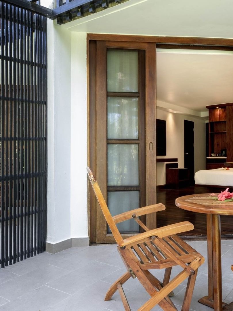 Wooden chairs and table with flowers on a balcony with garden view at Warwick Fiji Resort and Spa in Korolevu.