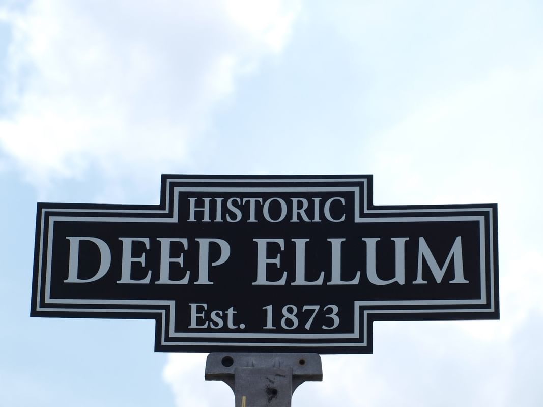 Historic Deep Ellum sign under a cloudy sky near Warwick Melrose Dallas