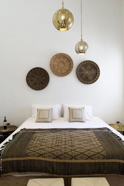 Bedroom with Woven Decor Bed with a patterned throw by side tables under woven wall plates at NOI Blend Colchagua