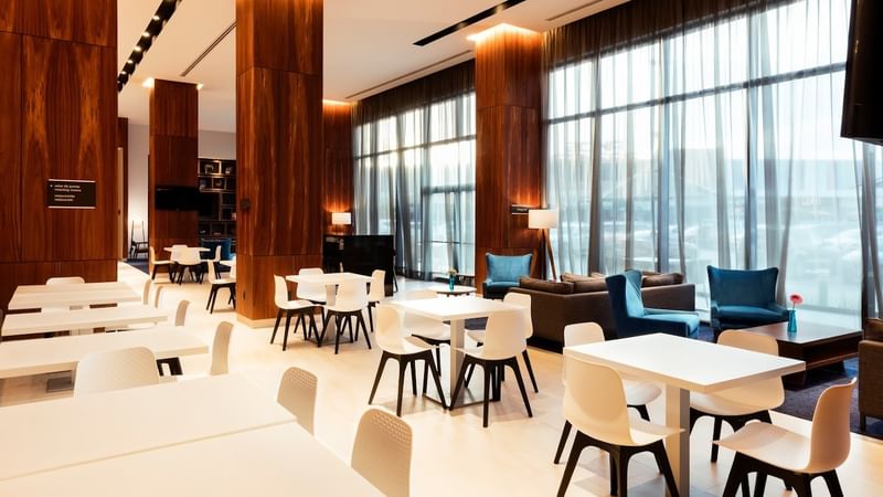 Dining area at Fiesta Inn Express Cancún Cumbres featuring tables near a lounge by the window, best restaurants in Cancun