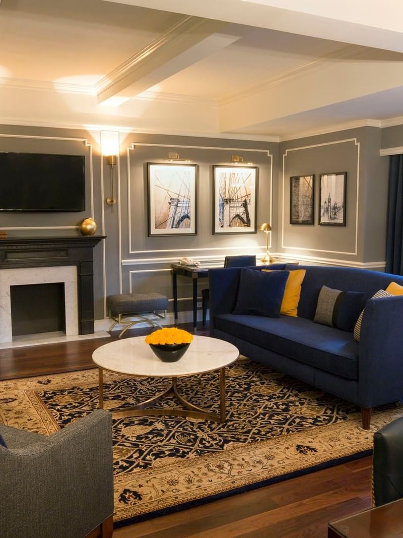 Living area with a blue velvet sofa & yellow chairs and marble coffee table in Randolph Suite at Warwick New York