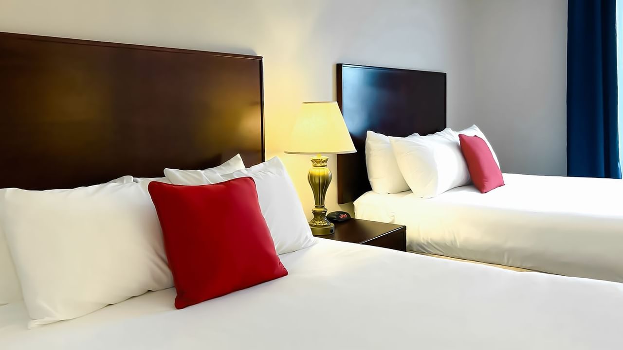 Hotel bedroom with two queen beds, night stand, and lamp