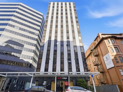 Tall building with UniLodge logo among other structures in urban setting.