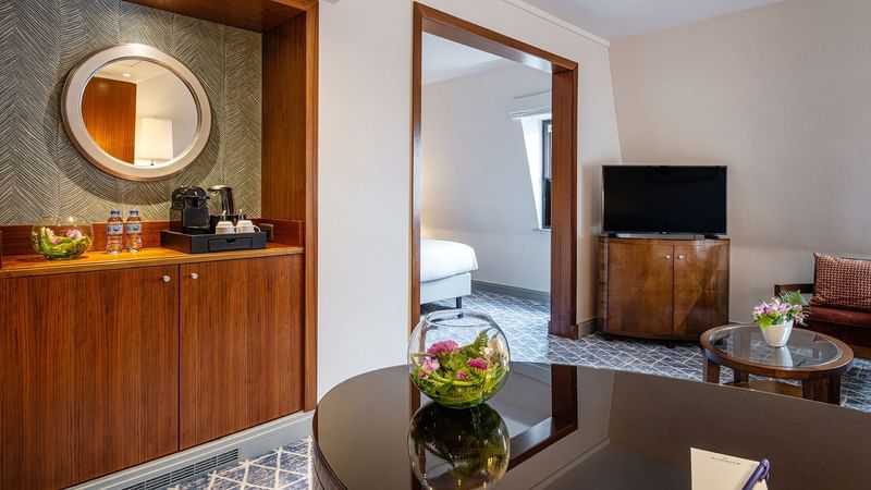 Living area with table and wooden cabinet in Junior Suite at Warwick Brussels