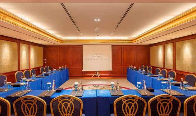 Titanic Deluxe Golf Belek'teki Convention Center'da U şeklinde masa düzeni ve projeksiyon perdesi.