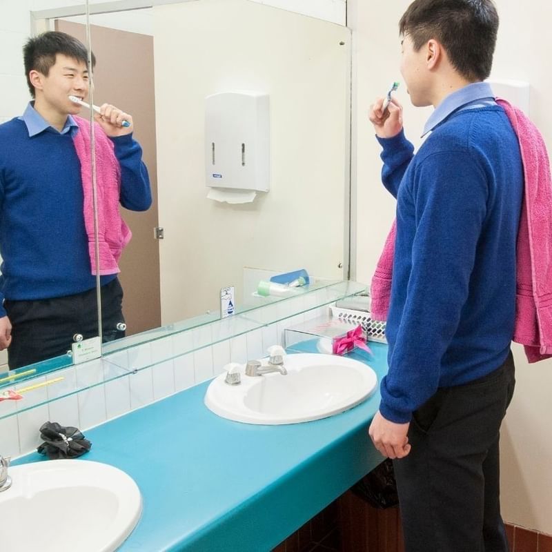 Student brushing teeth in a bathroom with two sinks at La Trobe University - Units.