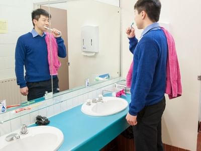 Student brushing teeth in a bathroom with two sinks at La Trobe University - Units.