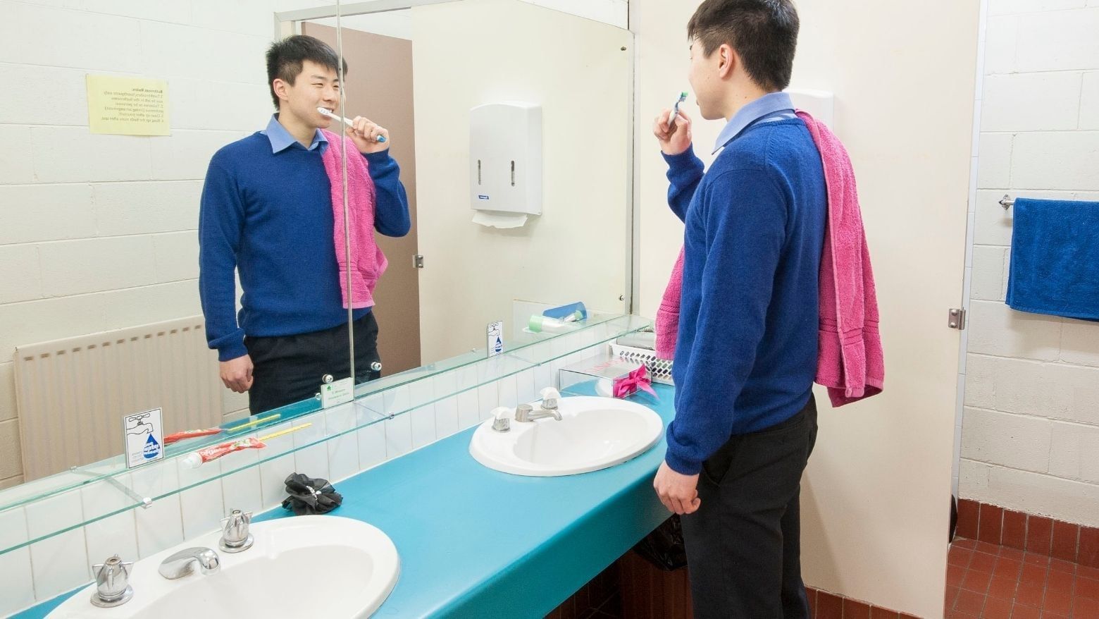 Student brushing teeth in a bathroom with two sinks at La Trobe University - Units.