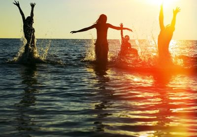 Friends playing in the ocean water at sunset