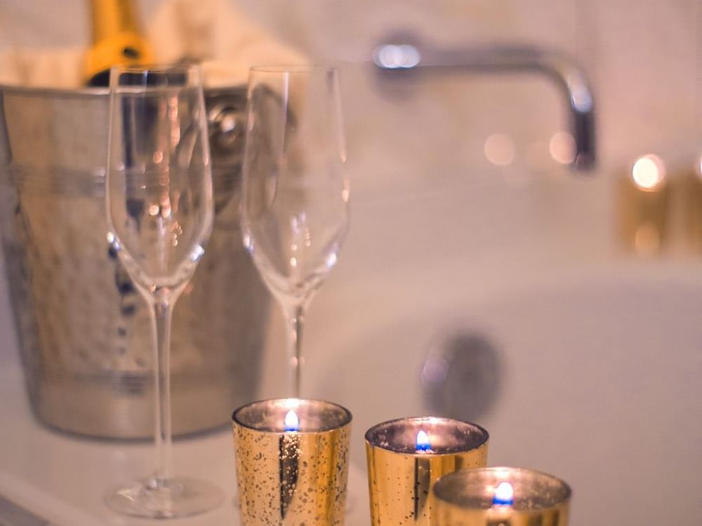 Wine bucket, bottle of wine, wine glasses and candles next to tub
