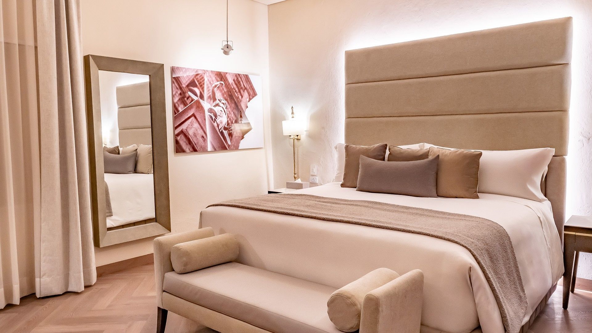 King Real featuring a plush king bed, a large tan headboard, framed artwork, and a full-size mirror at Quinta Real Puebla