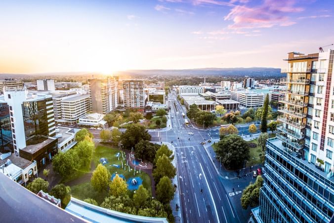 Panoramic view of the cityscape with urban buildings, busy roads, and a green park near Ibis Adelaide