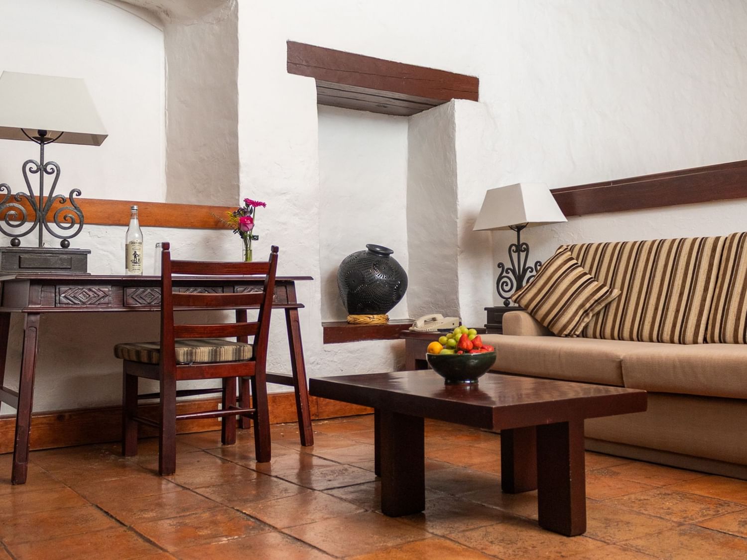Sala de estar Suite Gobernador King con muebles de madera y cesta de frutas en Quinta Real Oaxaca de Juárez