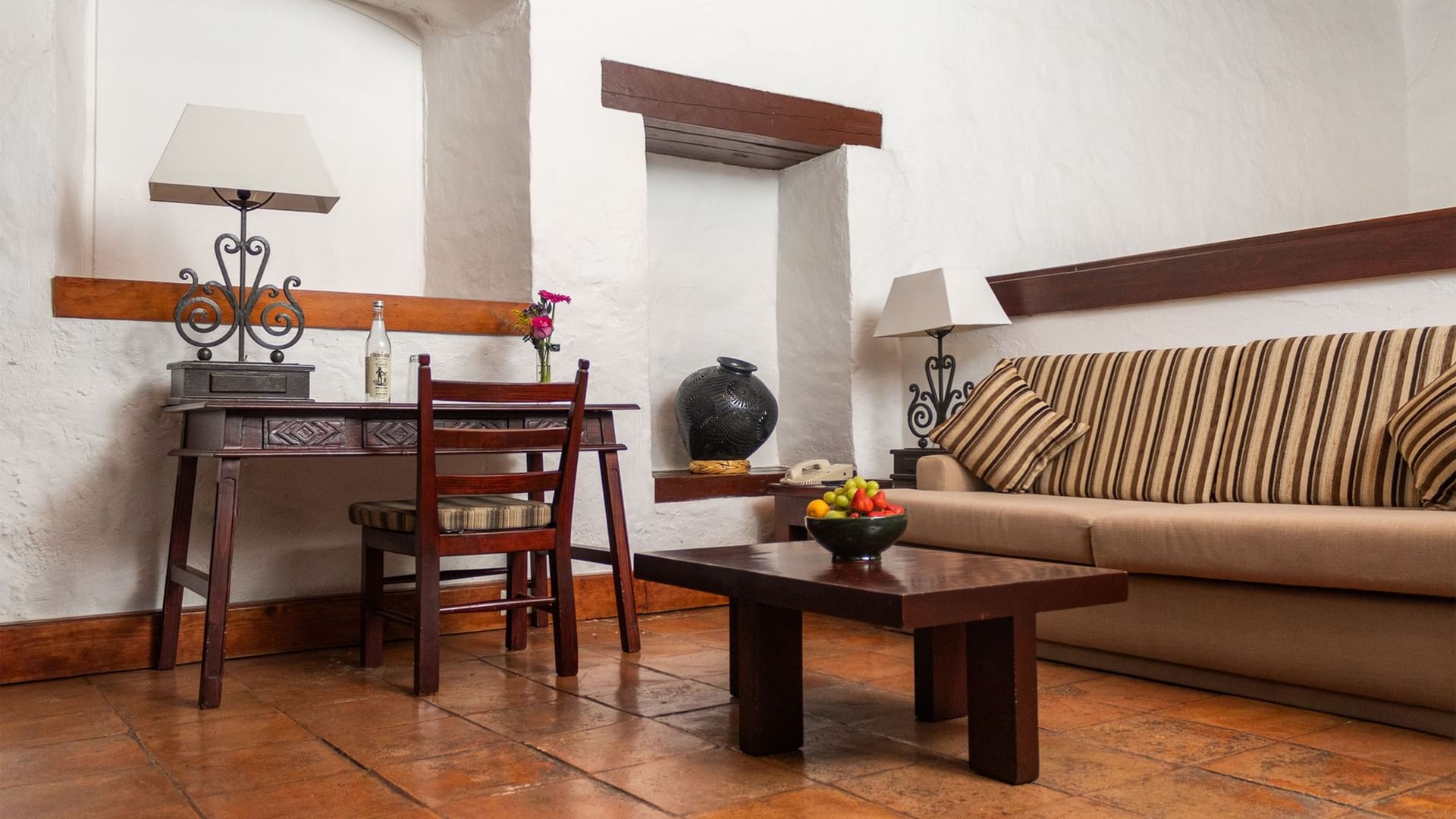 Sala de estar Suite Gobernador King con muebles de madera y cesta de frutas en Quinta Real Oaxaca de Juárez