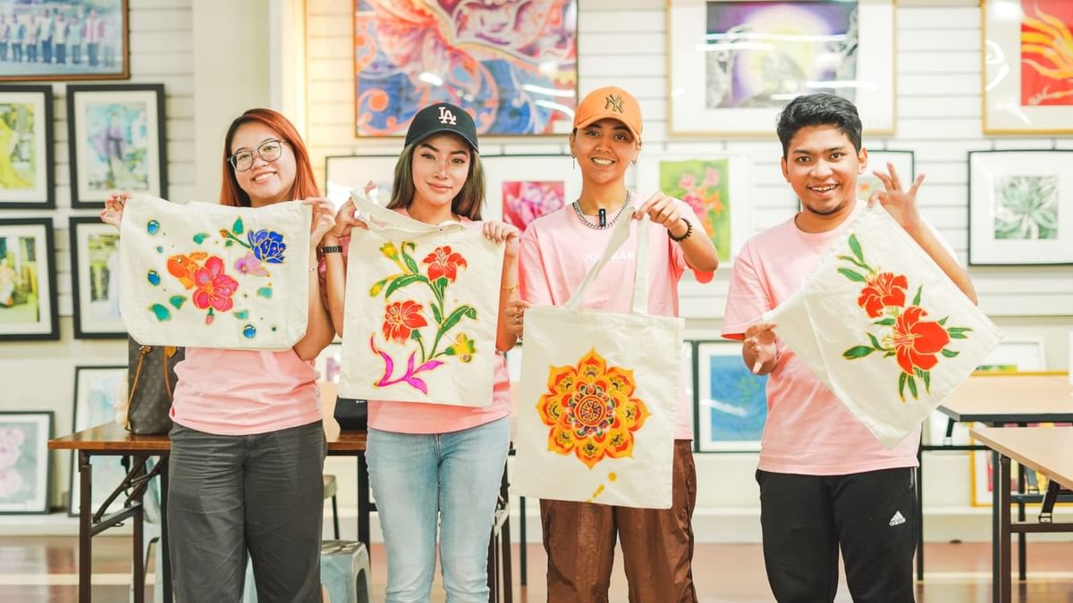 Four happy guests showing their painted tote bags in an art workshop at Sunway Velocity Hotel