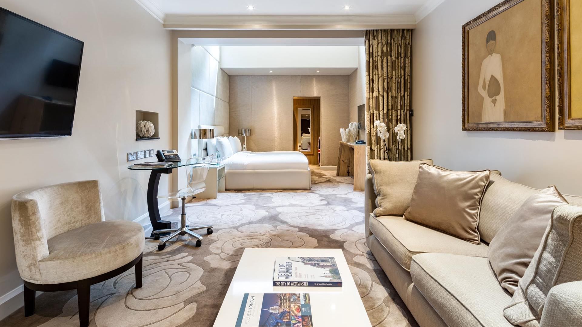 Chic Studio Suite in neutral tones at The May Fair Hotel, with a plush sofa, elegant artwork, sleek desk, and cozy bed
