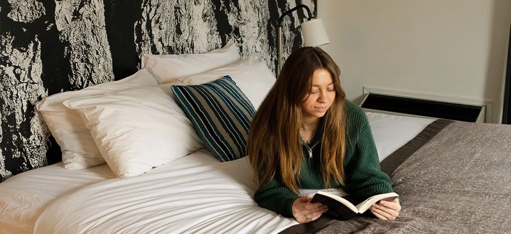 A person and their dog stand on a cliff's edge, admiring the mountain view near Canmore in the summer.