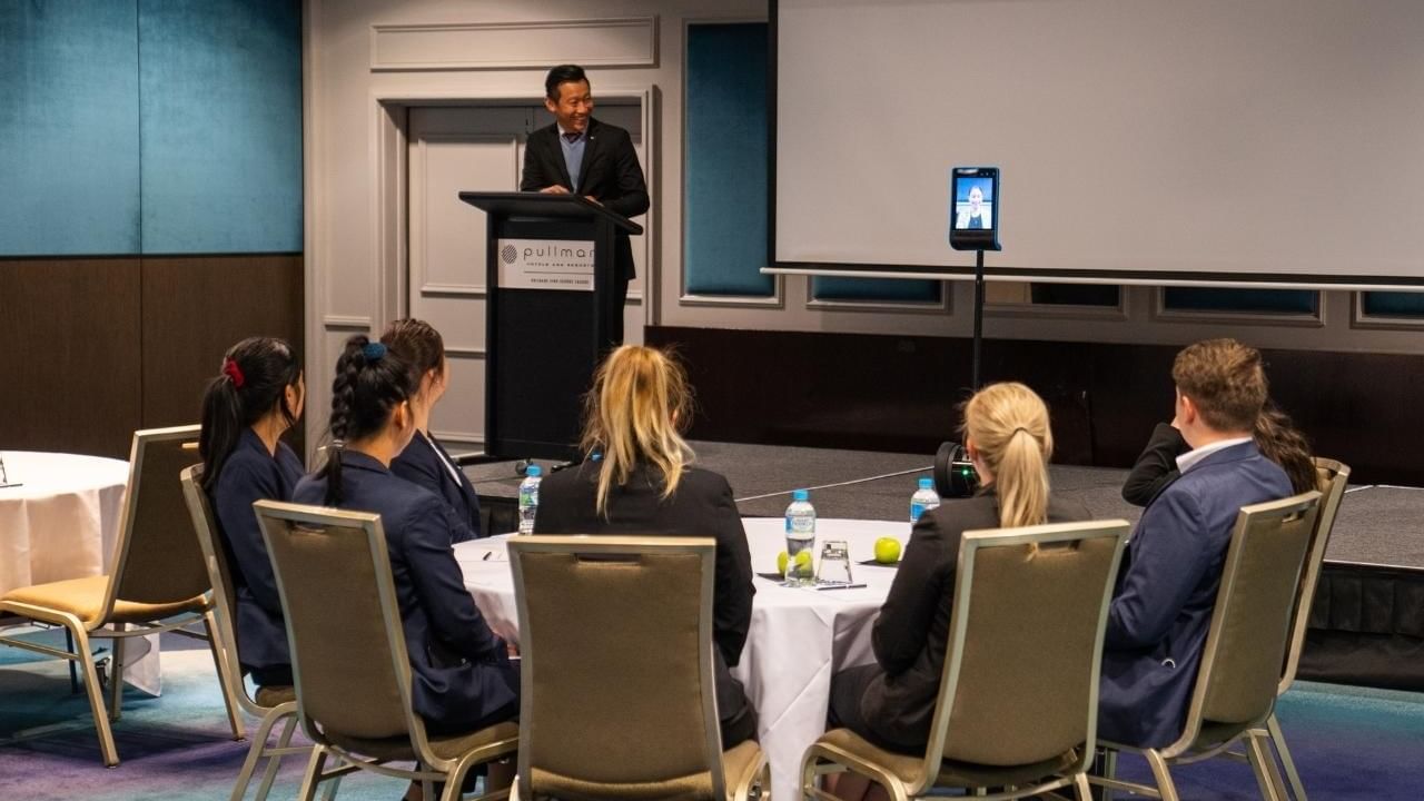 A man standing at a podium with a group of people sitting around it at Pullman King George Square